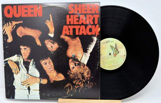 Queen's 'Sheer Heart Attack' vinyl LP album with the cover standing beside the black record on a small wooden stand against a white background.
