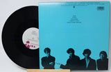 Vinyl record with a blue cover featuring black silhouette images of four people.