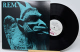 Vinyl record with a cover featuring a stylized face and 'R.E.M.' branding.