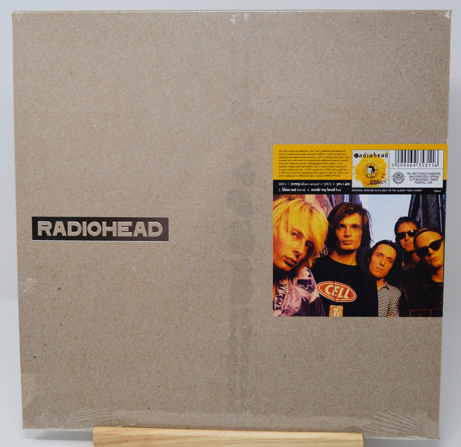 Radiohead 'The Endless Peace' vinyl LP album cover in its shrink wrap, displayed on a small wooden stand against a white background.