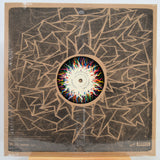 Vinyl record LP in shrink wrap with abstract geometric artwork in tan and black, featuring a colorful circular center label. The record label is visible in the center.