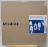 Radiohead 'The Endless Bed' vinyl record LP cover, sealed in plastic shrink wrap and displayed on a small wooden stand against a white background.