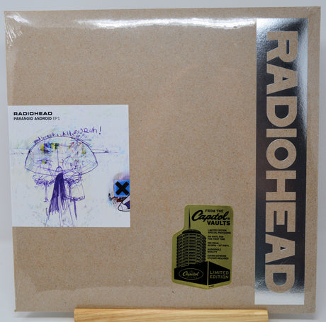 Radiohead 'Paranoia Argentinia' 12-inch vinyl record cover, limited edition, featuring a textured kraft-paper background, a vertical black band with gold 'RADIOHEAD' text, and a white album art insert on the left.