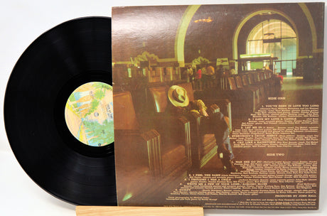 Vinyl record with cover showing a person in a hat sitting in an airport lounge.