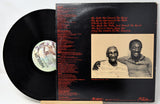 Vinyl record with a black and white cover featuring a group of people and a desert landscape.