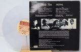 A vinyl record partially pulled from its black back cover, showing the track listing and band photos for Randy Roos's 'Mistral'. The record is translucent white with a beige label, displayed on a wooden stand against a white background.
