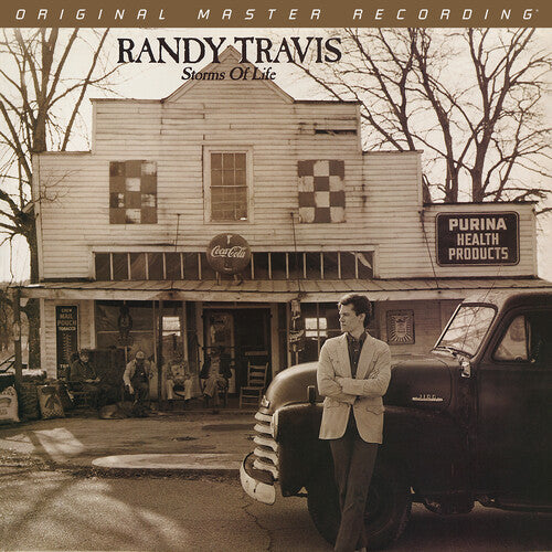 Album cover featuring a man standing in front of an old building with vintage cars and signs.