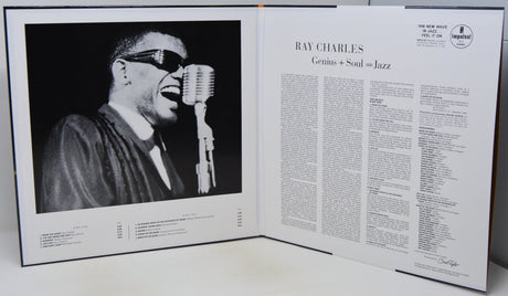 An open book or magazine spread showing a black-and-white photograph of Ray Charles singing into a microphone on the left page, with article text about Ray Charles on the right page.