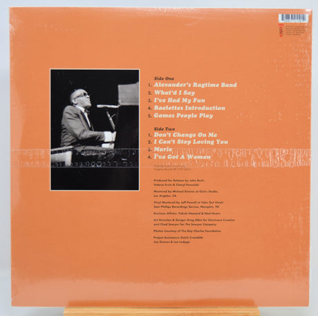 The back cover of a vinyl record by Ray Charles featuring an orange background, a black-and-white photo of him, and a tracklist.
