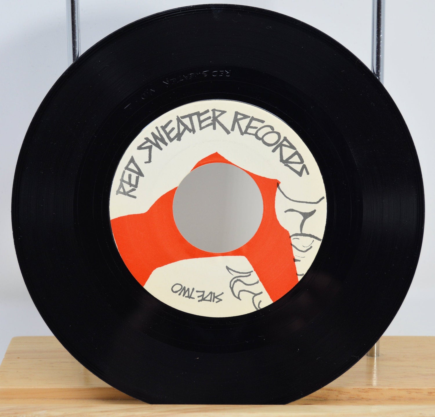 Close-up of Red Sweater Records vintage 7 inch vinyl with custom red and cream label design