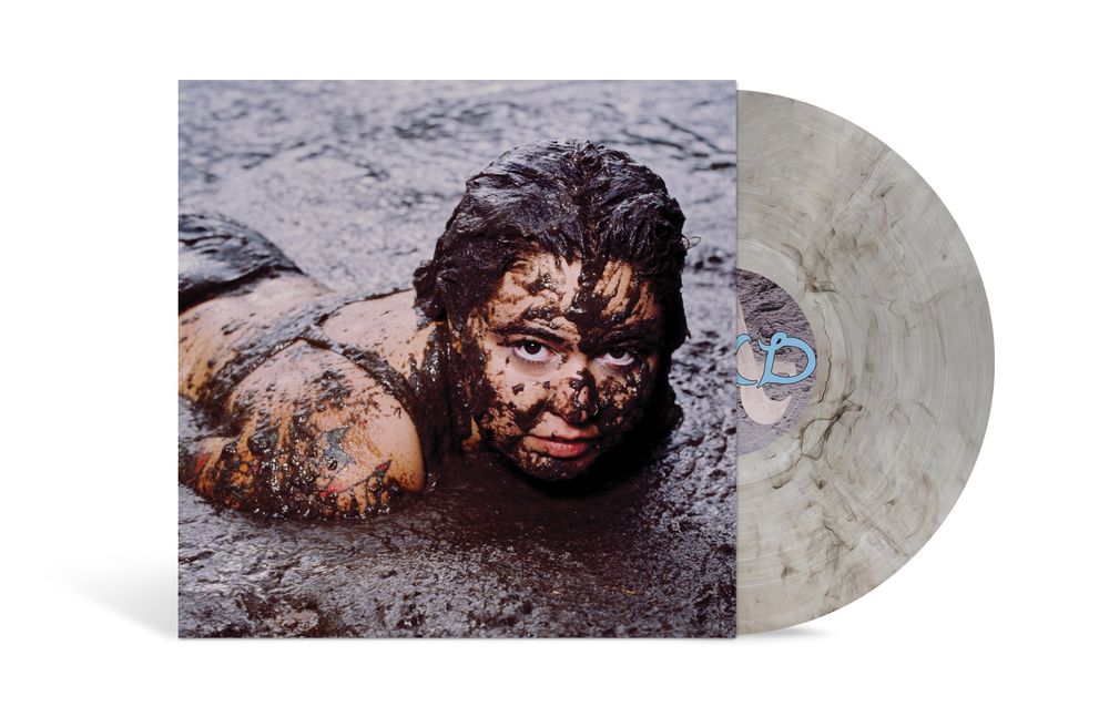 A vinyl record album shown at an angle with the sleeve featuring a photo of a person covered in mud, alongside a translucent marbled light gray record on a white background.