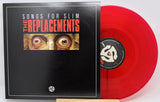 A vinyl record album shown with its black cover in front and a translucent red record partially visible behind it on a white background.