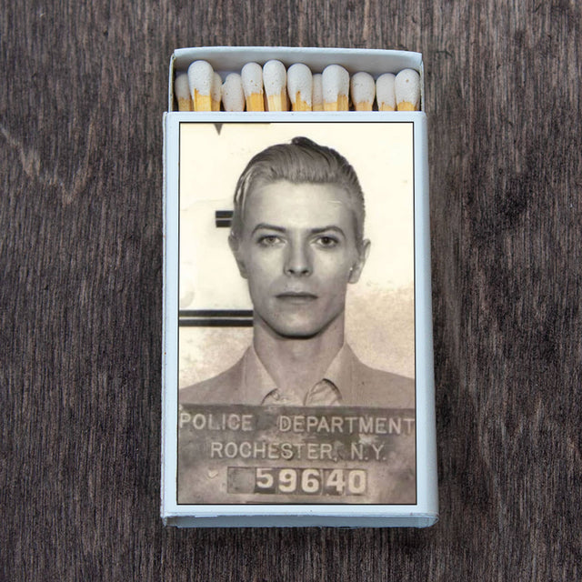 Open matchbox with vintage mugshot of a young man on the cover, set on a dark wood surface