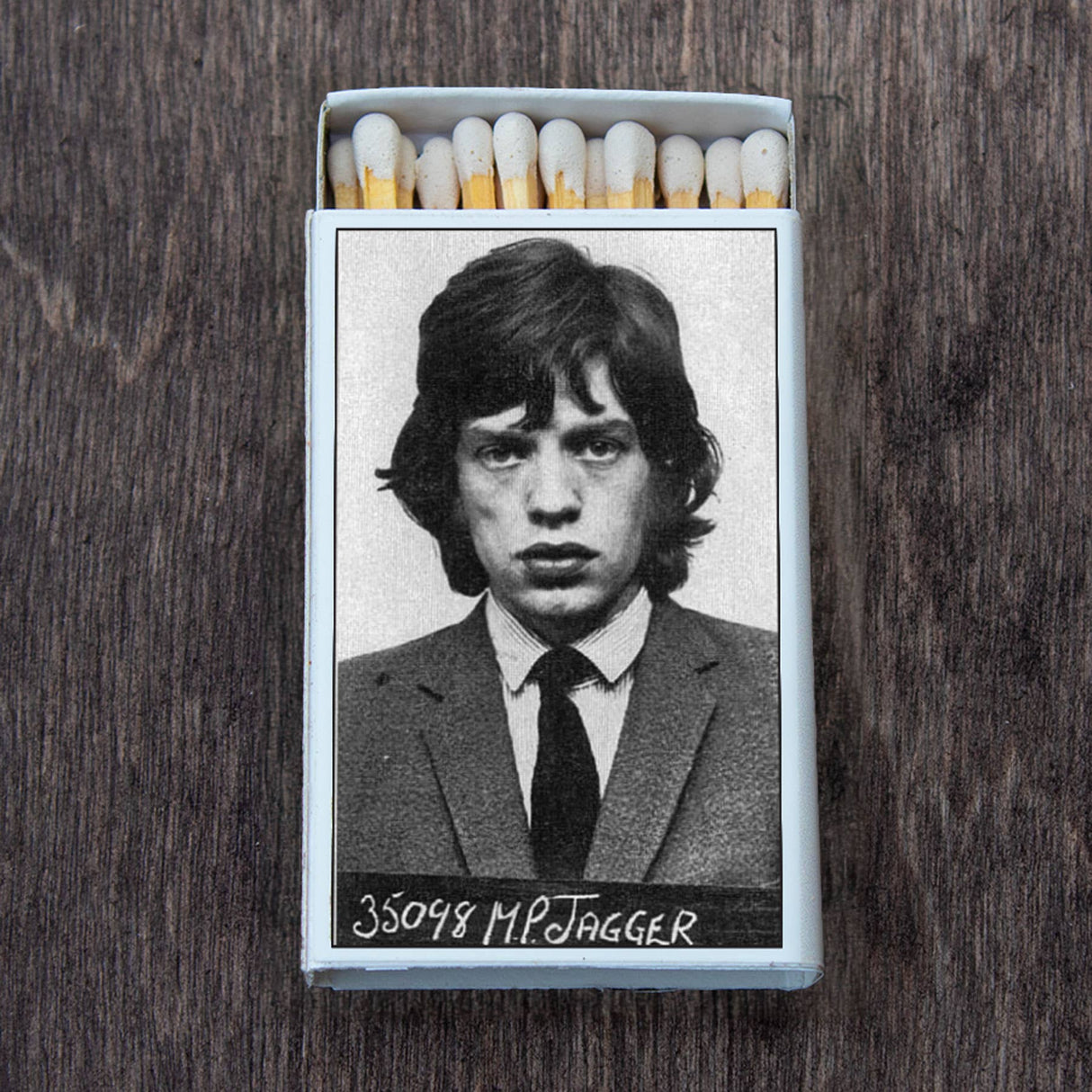 Matchbox featuring a black and white mugshot of a young man in a suit on a wooden surface