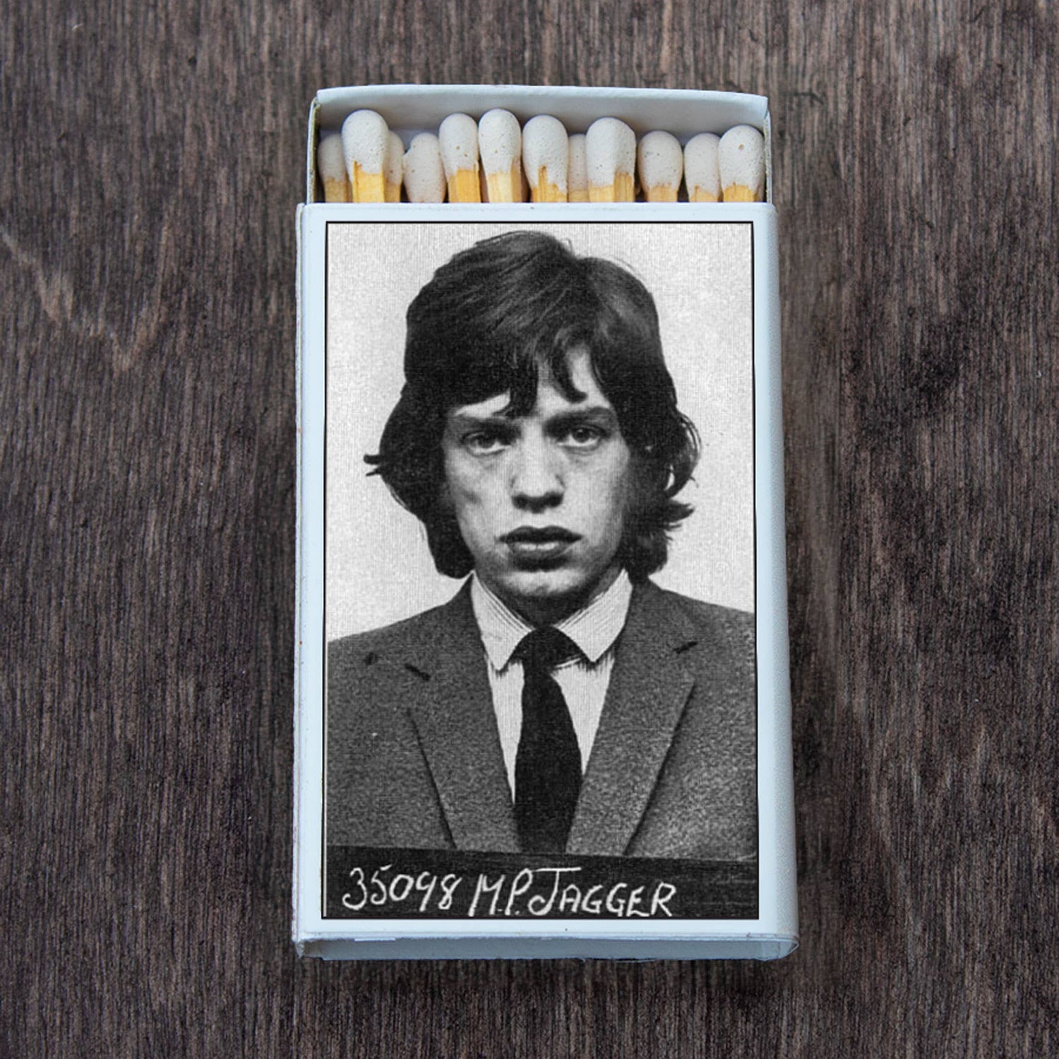 Matchbox featuring a black and white mugshot of a young man in a suit on a wooden surface