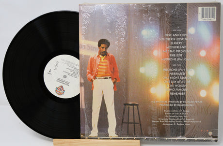 Vinyl record with cover featuring a person in an orange jacket and white pants against a blurred background.
