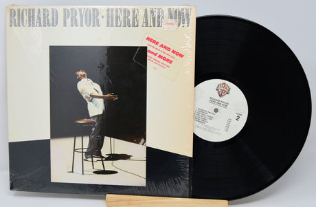 Vinyl record and cover titled 'Here and Now' by Richard Pryor on a light gray background