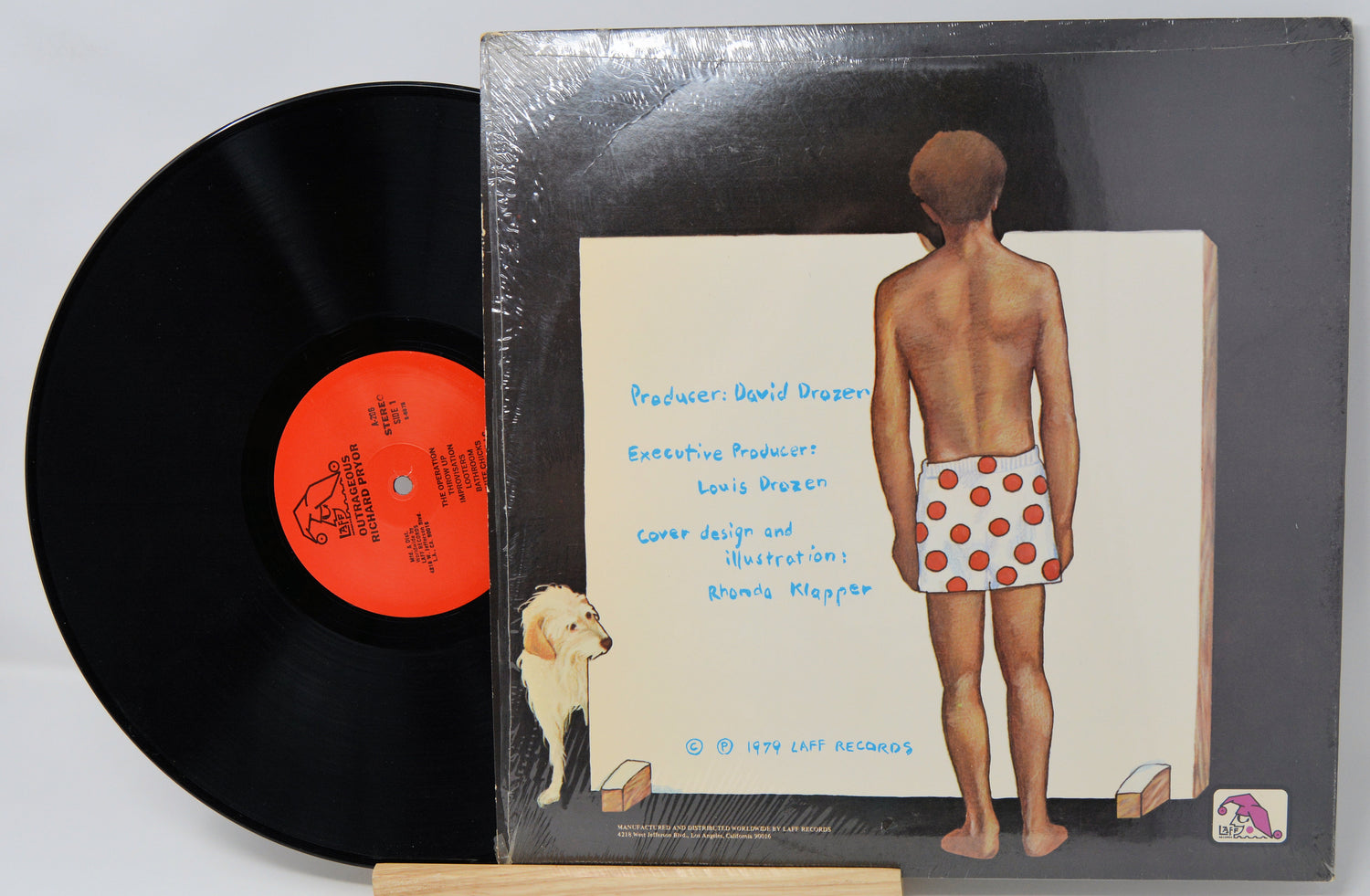 Vinyl record with a colorful label featuring a person in polka dot shorts and a dog.