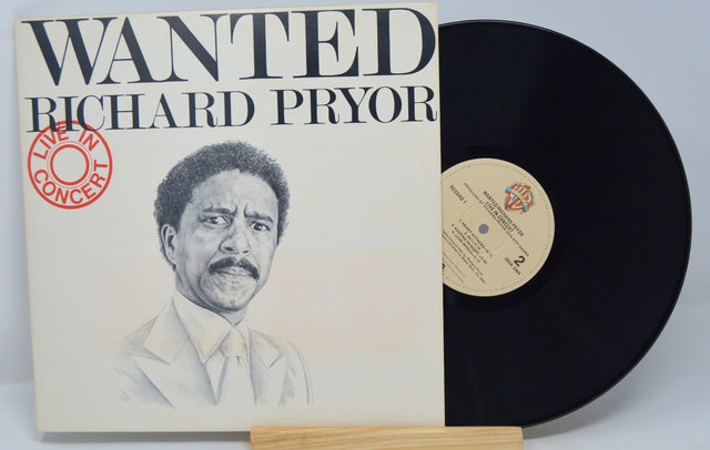 A vinyl record titled 'Wanted Richard Pryor' with an illustration of Richard Pryor on the cover, placed next to its case.