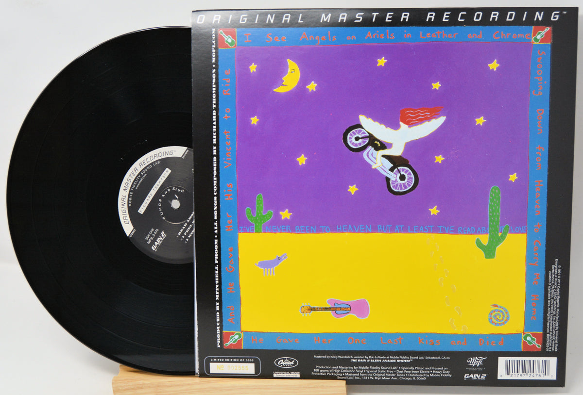 A vinyl record partially pulled from its illustrated outer sleeve, photographed on a light background. The sleeve reads 'Original Master Recording' and shows a colorful desert scene with a motorcycle, cacti, stars, and a purple sky.