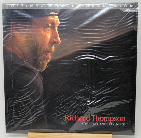 Richard Thompson's 'Some Enchanted Evenings' 45rpm vinyl record, sealed in its original plastic shrink wrap. The cover art features a dramatic portrait of the artist in profile against a dark, textured background with red and white text.