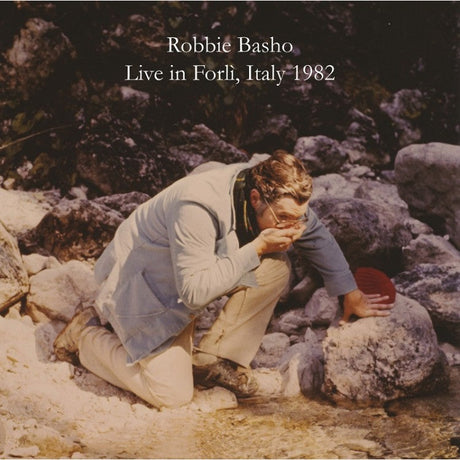 Robbie Basho drinks water from a mountain stream with album title Live in Forlì, Italy 1982