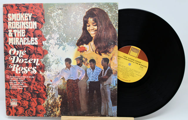 Vinyl record with cover featuring Smokey Robinson & The Miracles' 'One Dozen Roses' on a light blue background.