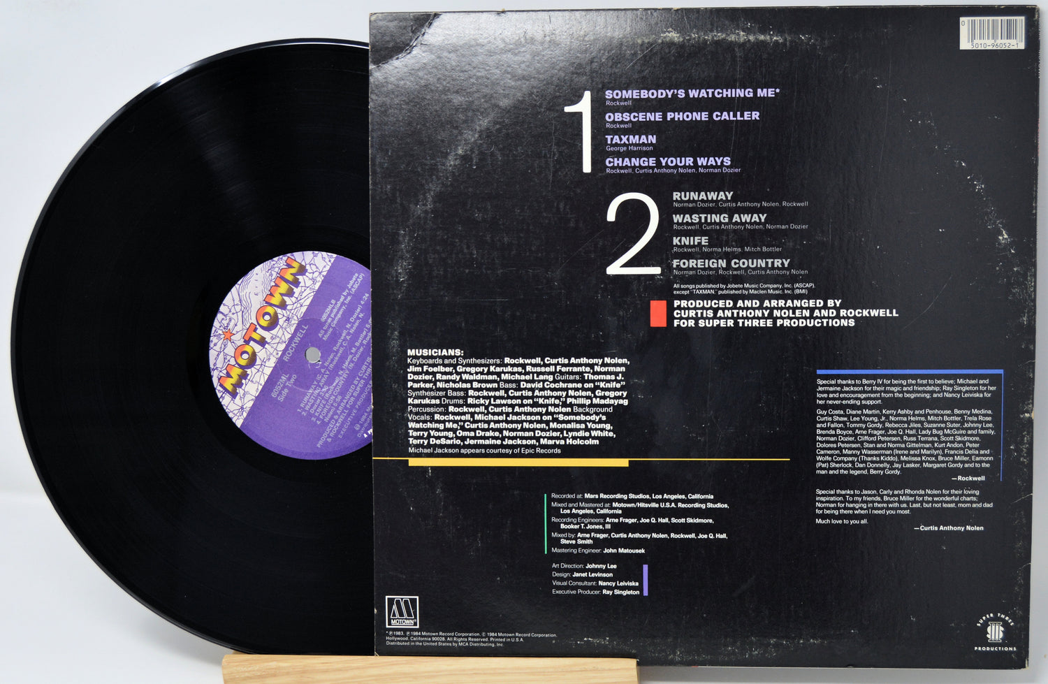 Vinyl record with cover displaying tracklist and album art on a white background