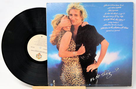Vinyl record with a cover featuring two people embracing, set against a blue sky.
