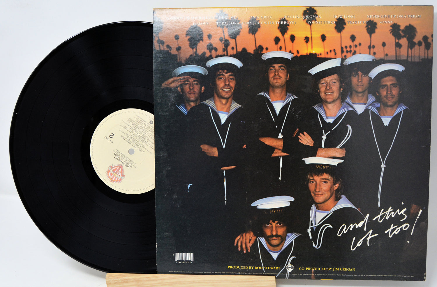 Vinyl record with a cover featuring a group of people in sailor outfits against a sunset palm tree background.