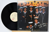Vinyl record with a cover featuring a group of people in sailor outfits against a sunset palm tree background.