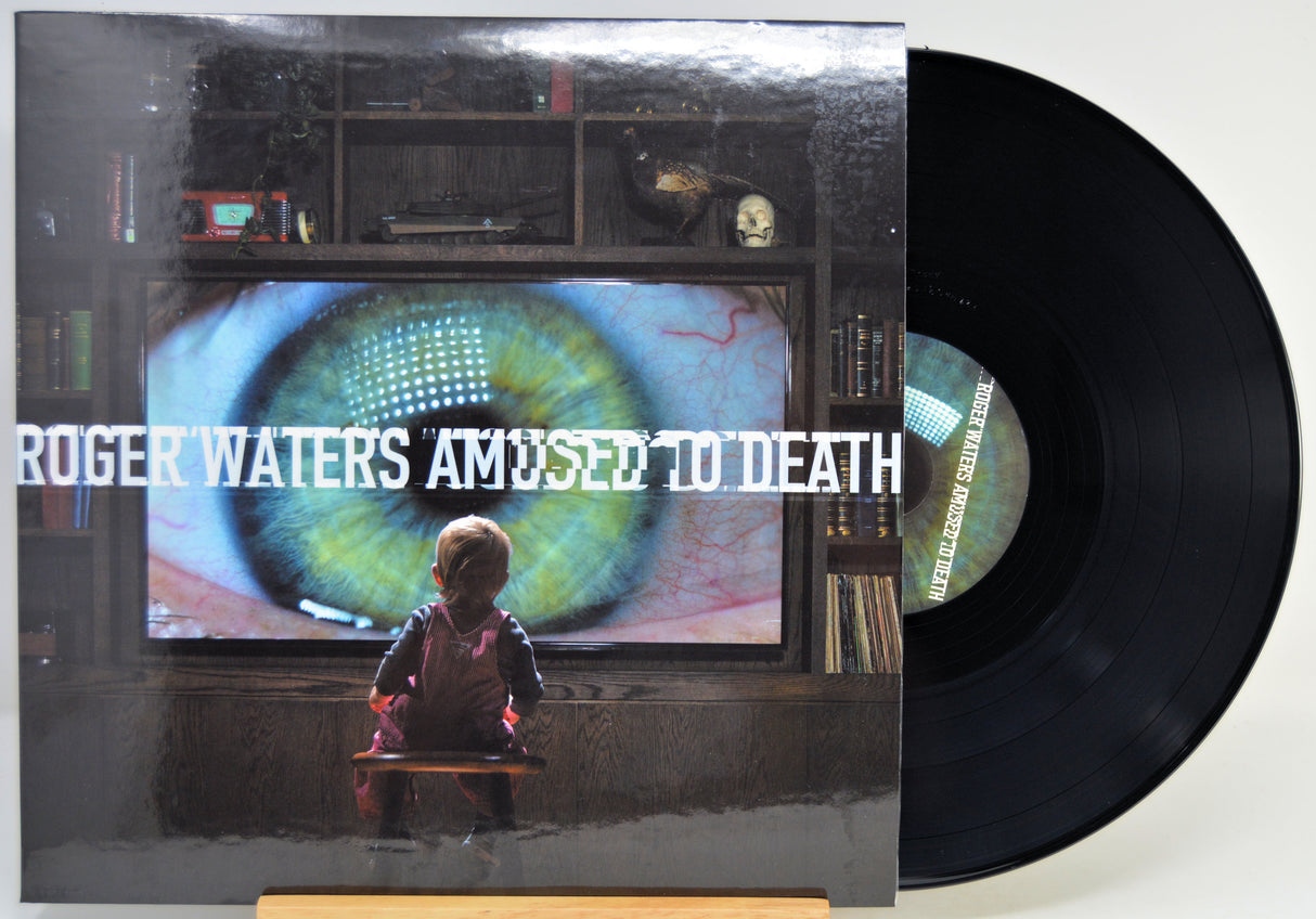 Roger Waters 'Amused to Death' vinyl record LP with its illustrated cover jacket and a black vinyl record partially visible, photographed against a plain light background.