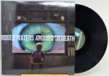 Roger Waters 'Amused to Death' vinyl record LP with its illustrated cover jacket and a black vinyl record partially visible, photographed against a plain light background.