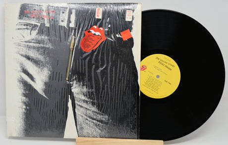 Vinyl record with a black and white cover featuring a zipper and red tags.