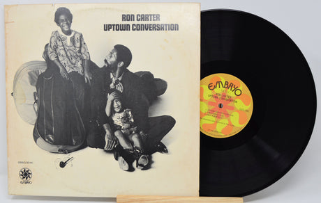 Ron Carter's 'Uptown Conversation' vinyl record LP, showing the cream-colored album cover with black-and-white cover art and the black record partially pulled out, revealing a yellow and orange 'Embryo' label.