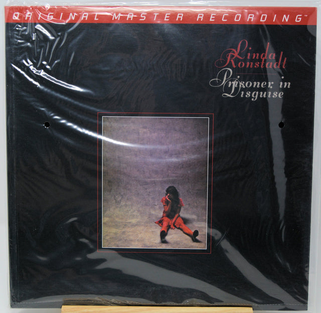 Linda Ronstadt's 'Lizonez in Disguise' original master recording vinyl LP album cover, sealed in its original plastic shrink wrap. The cover is predominantly black with a red banner at the top and a central square album art photo depicting Linda Ronstadt in a red outfit.