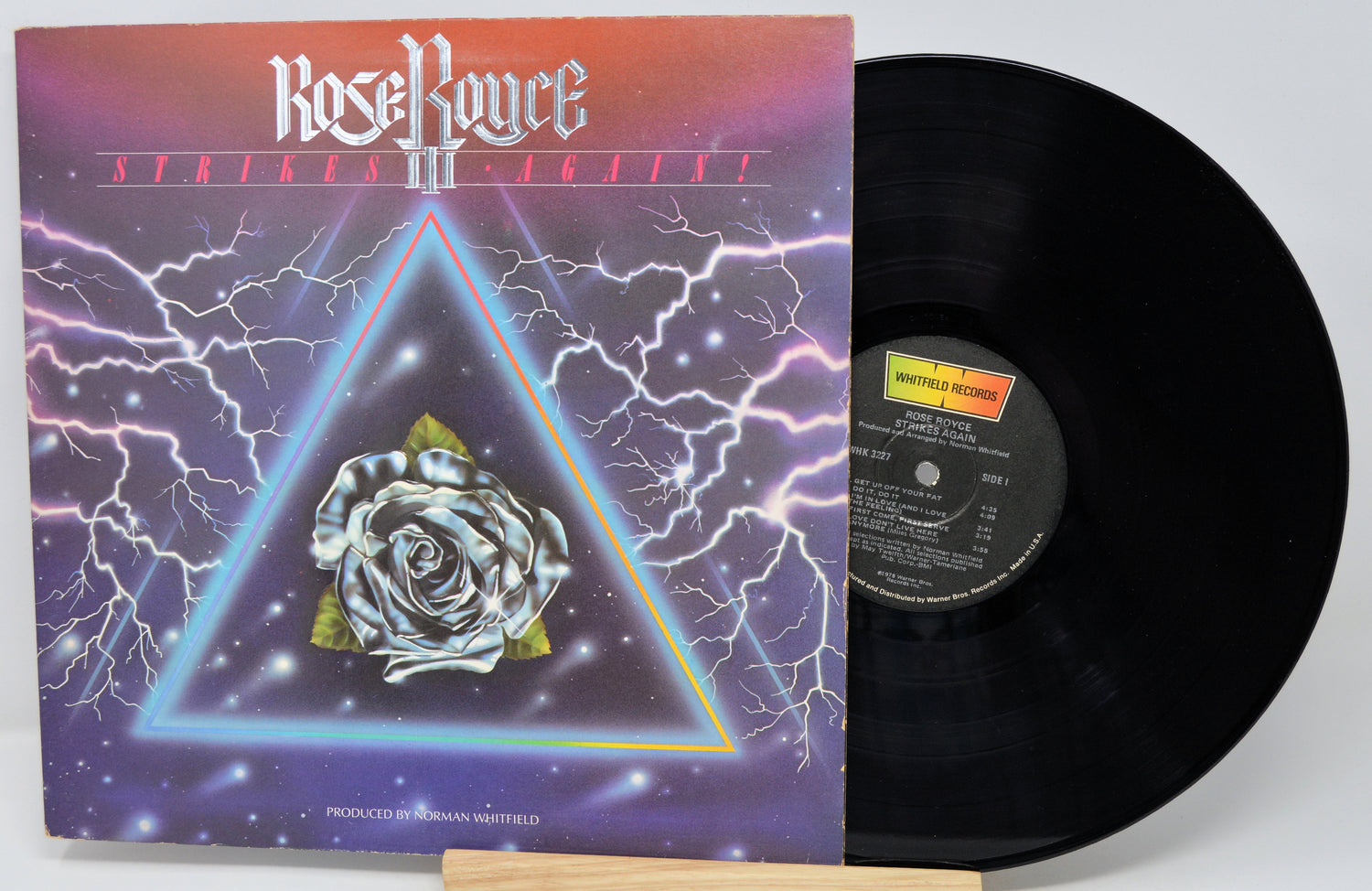 Vinyl record with cover featuring a rose and triangle design on a white background
