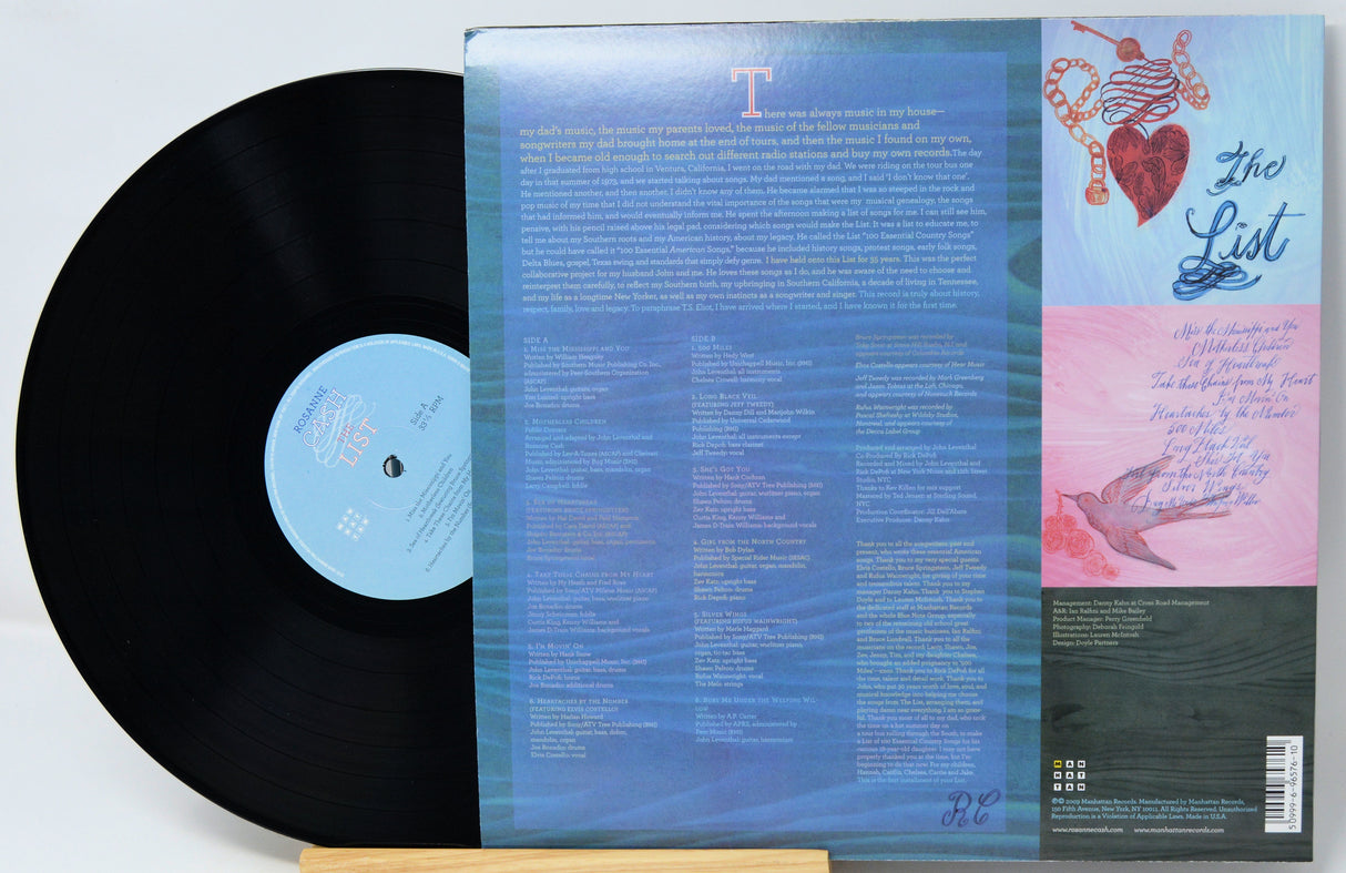 Vinyl record album shown with the black LP partially pulled from the back cover, which features a blue gradient center, song lyrics, and a pink-and-blue illustrated side panel. The record label reads 'The List'.