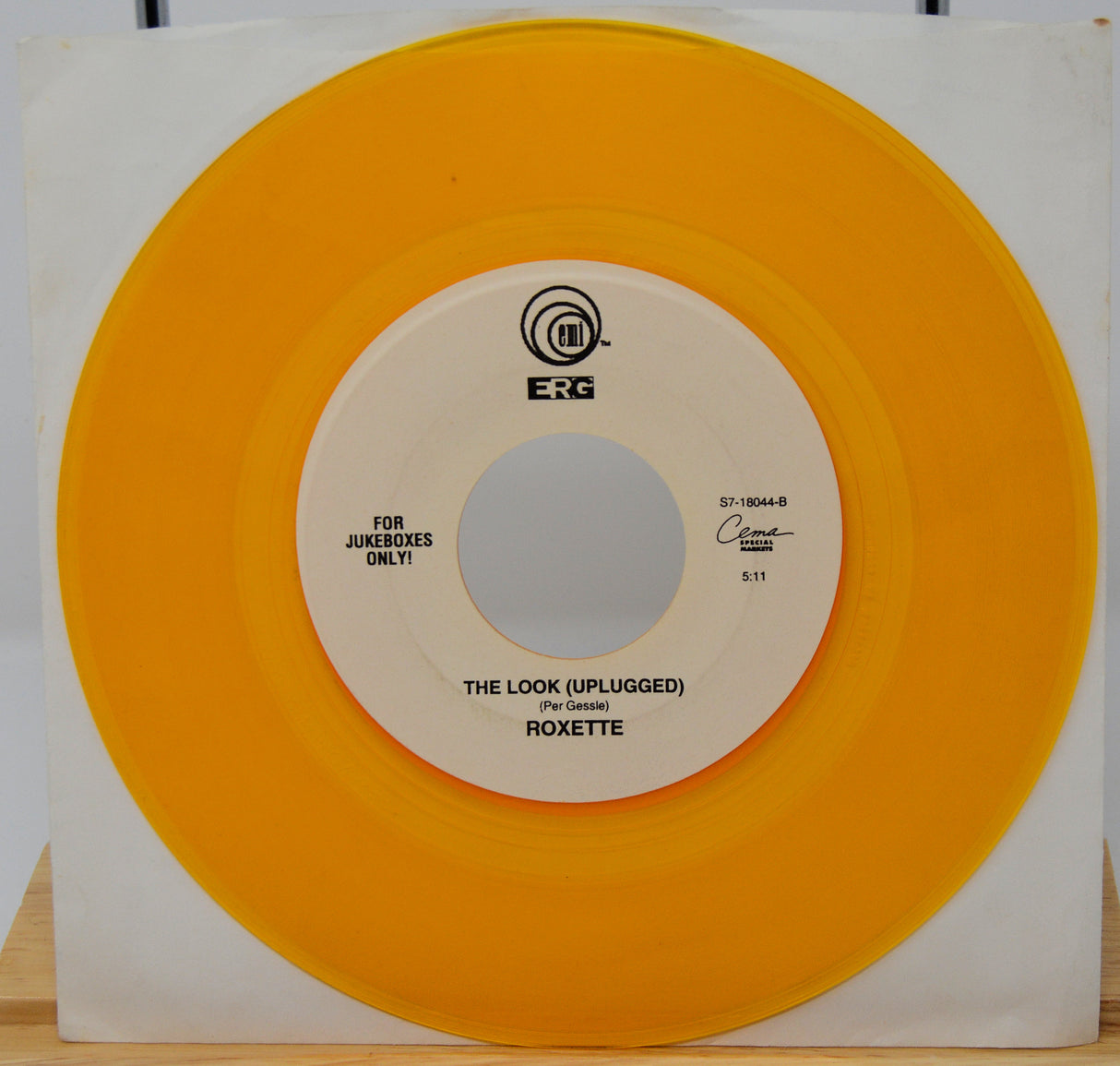 Vinyl record with orange outer sleeve and white inner label on a wooden surface