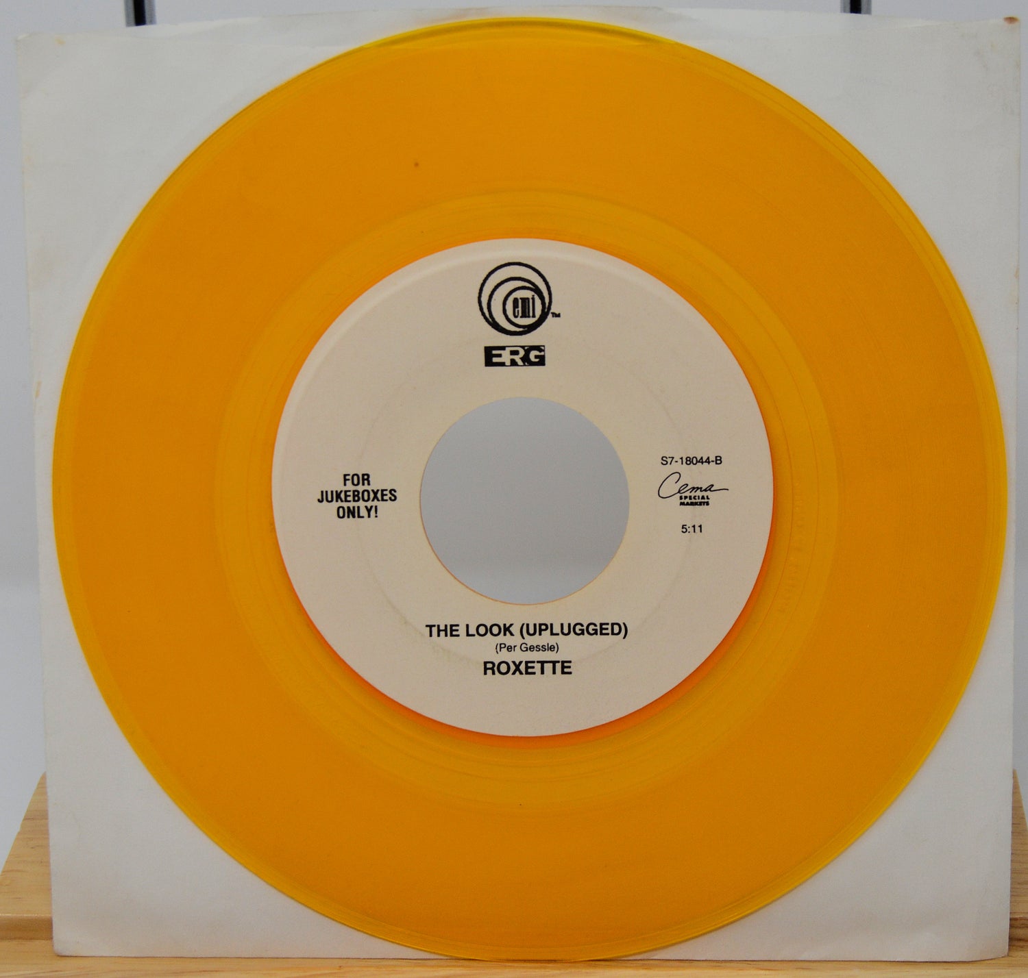 Vinyl record with orange outer sleeve and white inner label on a wooden surface