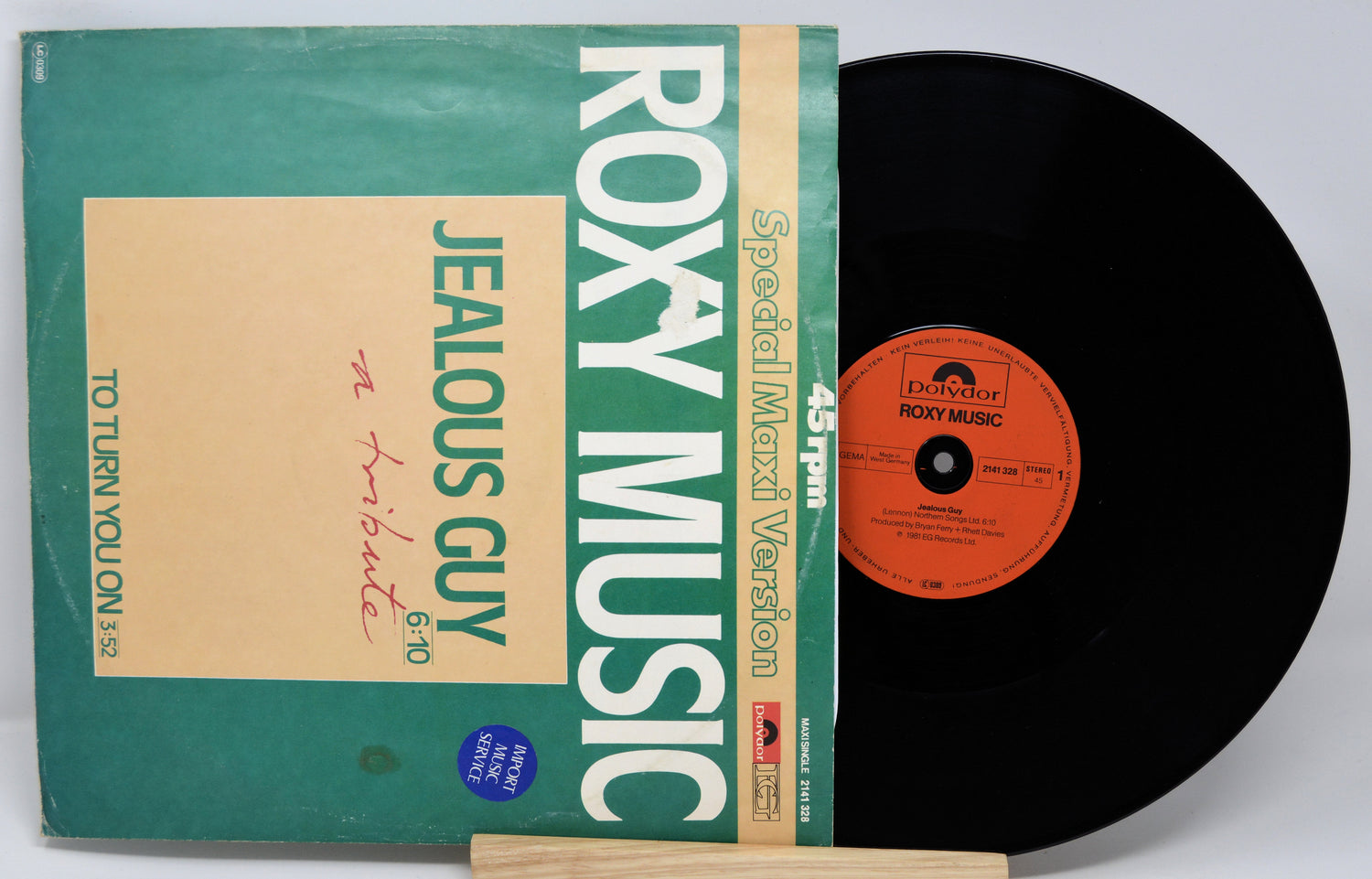 Vinyl record with green cover featuring 'Roxy Music' and 'Jealous Guy' text on a white background