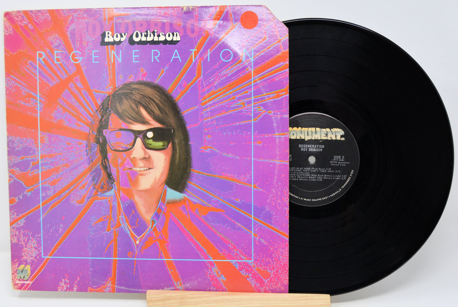 Vinyl record with a colorful cover featuring a person wearing sunglasses, on a white background.