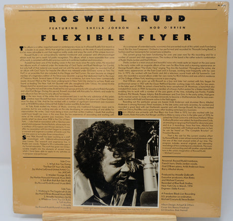 Album cover with text and a black and white photo of a man with a microphone.