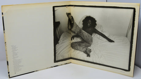 Open book with a black and white photograph of a person on a bed inside.
