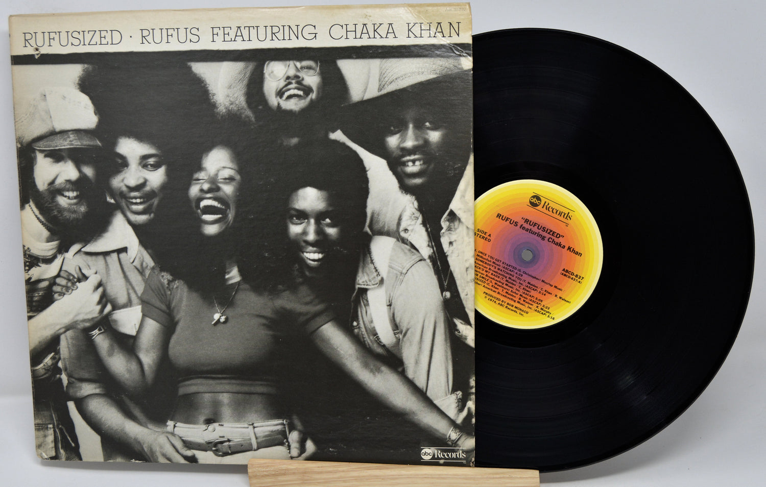 Vinyl record with cover featuring a group of people, including Chaka Khan, on a white background.