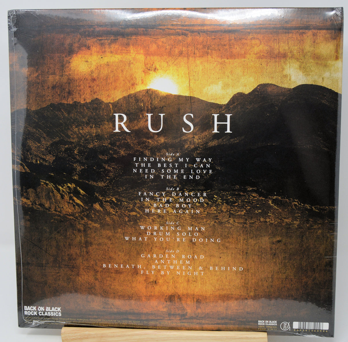 Rush - Back on Black Rock Classics vinyl record album cover, showing a dramatic mountain landscape under a golden sunset sky with the band name 'RUSH' in large white letters.