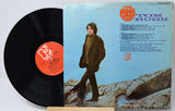 Vinyl record with cover featuring a person walking on rocks