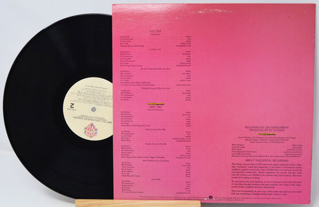 Vinyl record with a pink label and black disc on a white background