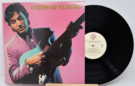 Vinyl record with a pink cover featuring a person playing guitar, on a white background.