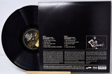 Vinyl record with cover displaying text and a photo of a person playing guitar.